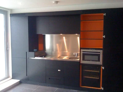 black kitchen with sink, oven and orange drawers from inside